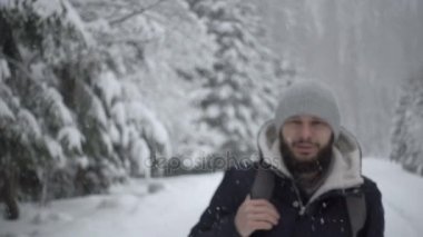 Kış ormanda ayakta neşeli sakallı yakışıklı genç portresi. Ağır çekim
