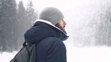 Kış ormanda ayakta neşeli sakallı yakışıklı genç portresi. Ağır çekim