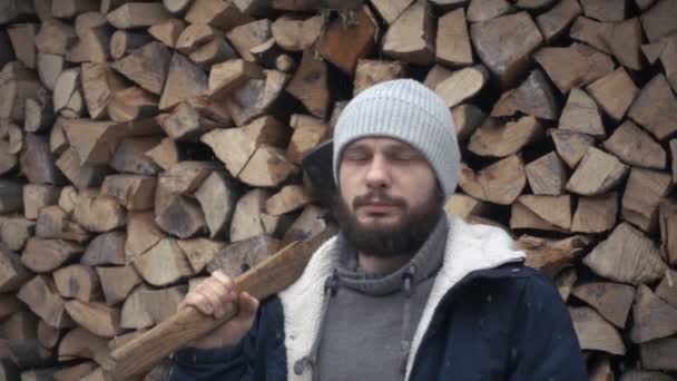 Человек дровосек с топором на фоне кучи дров — стоковое видео