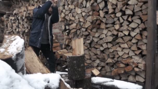 Людина розділяє заморожену деревину сокирою. широкий постріл повільний рух — стокове відео