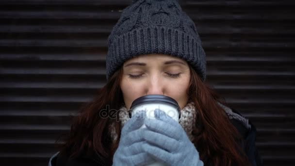 冬の屋外で温かい飲み物を持つ少女の顔。女の子がコーヒーを飲む熱い冬の朝、屋外都市. — ストック動画