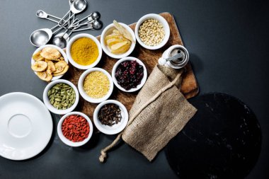 Çeşitli baharatlar ve otlar siyah ahşap zemin, üstten görünüm üzerine saydam bir kasede