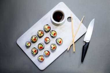 Vegan suşi quinoa, sebze ve soya fındık soslu beyaz bir plaka üzerinde açık renkli rulo. Vegan sağlıklı gıda kavramı.
