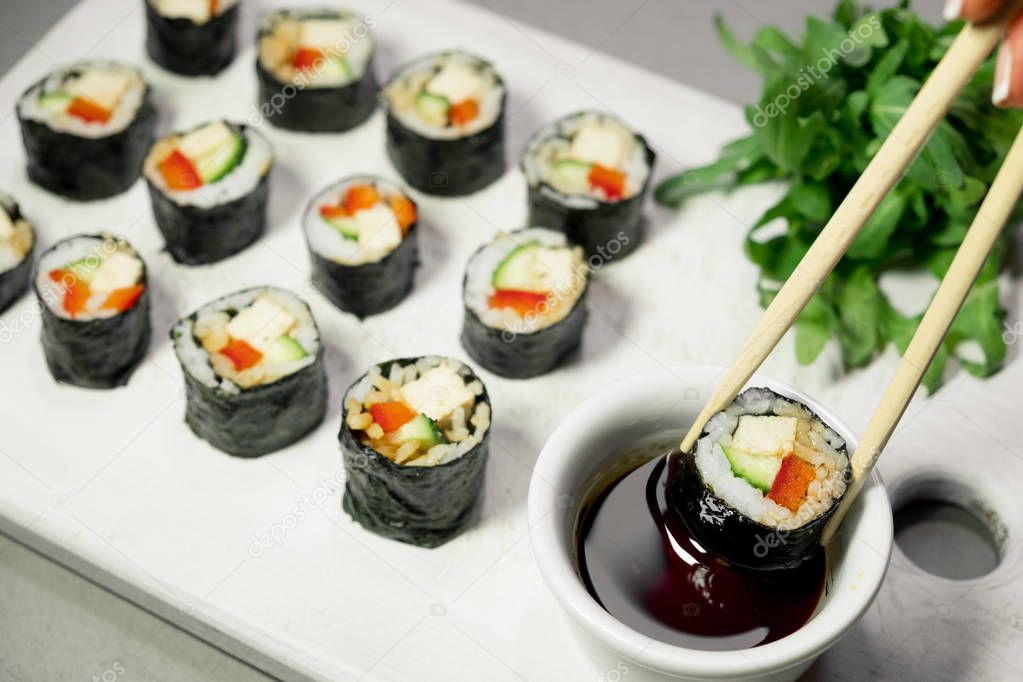 Vegan sushi rolls with quinoa, vegetables and soy-nut sauce on a white plate, light background. Vegan Healthy Food Concept.