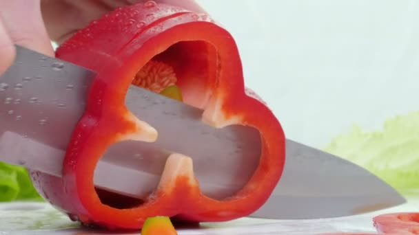 A faca corta a pimenta vermelha. Uma grande pimenta vermelha doce é cortada em uma tábua de corte. Feche, vista lateral. Pimenta búlgara . — Vídeo de Stock