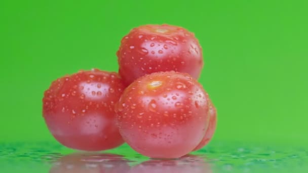 Red tomato with water drops, slowly rotating on green background, close up — Stock Video