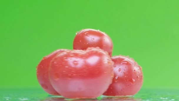 Kırmızı domates ile su damlaları, yavaş yavaş yeşil arka plan üzerinde dönen, yakın çekim — Stok video