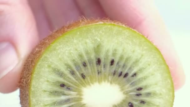 Kiwi being sliced in half on wet white background. Close up — Stock Video