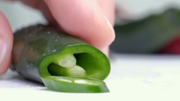 Chiles verdes picados con un montón de chiles verdes en el boarrd de corte wihte y fondo blanco. horizontal — Vídeos de Stock
