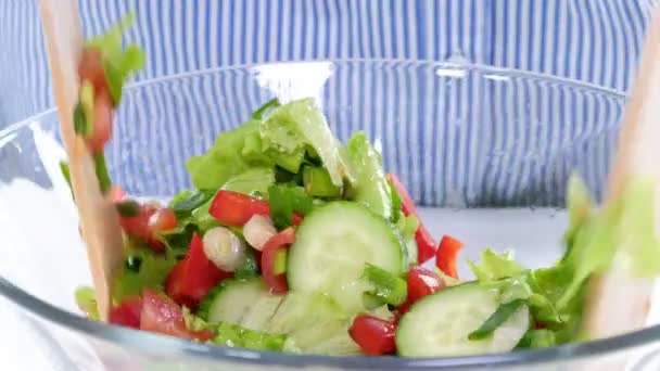 Mujer joven cocinando ensalada de verduras sobre fondo blanco. comida saludable, comida vegetariana — Vídeo de stock