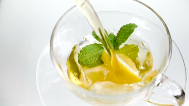 Té en taza con menta de hoja y limón sobre fondo blanco — Vídeo de stock