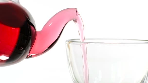 Röd ros te i en glas tekanna och en kopp på en vit bakgrund. — Stockvideo