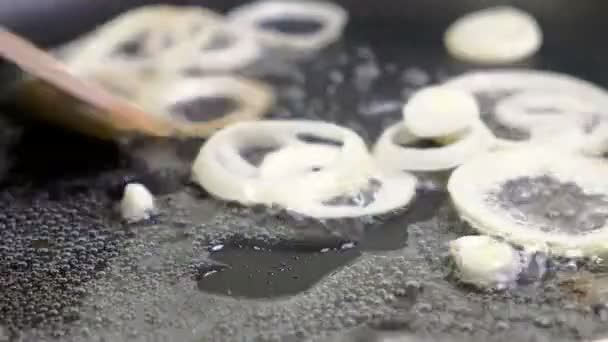 Cipolle tritate fritte in olio vegetale nella padella. Primo piano su una piastrella da cucina. Torrefazione su padella bollente . — Video Stock