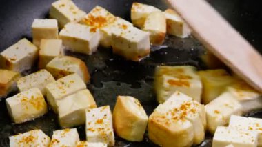 Bir dökme demir tava üzerinde baharat, vejetaryen diyet vejetaryen yemek yemek için sağlıklı madde ile Kızarmış tofu. Siyah bir zemin üzerine Kızarmış tofu.