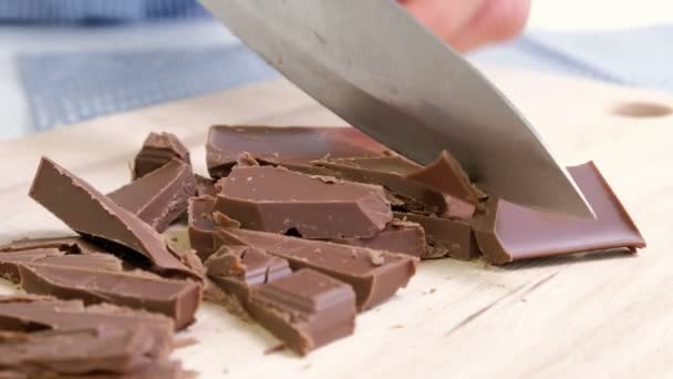 Μαγειρέψτε τα χέρια κοπή σοκολάτα μπαρ με ένα μαχαίρι κουζίνας σε ξύλο κοπής. — Αρχείο Βίντεο