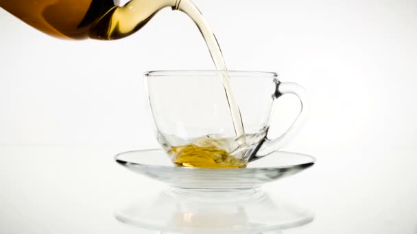 Tea pouring. Tea being poured into glass transparent tea cup. Tea time. Transparent glass teapot and teacup. Slow motion — Stock Video