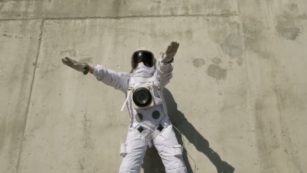 Funny astronaut makes dancing. Against a background of a concrete wall. — Stock Video