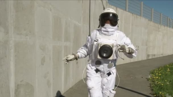 Funny astronaut makes dancing. Against a background of a concrete wall. 4K — Stock Video