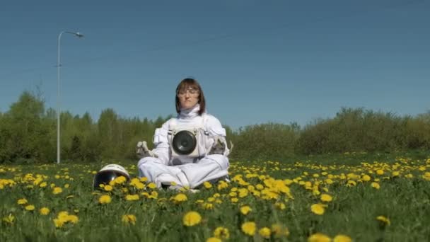 Kosmonautin übt Meditation auf einem Blumenfeld — Stockvideo