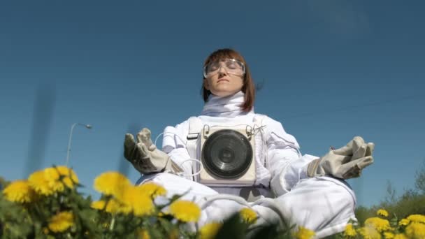 Dívka kosmonaut praktikující meditaci na květinové pole — Stock video