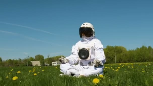 Chica cosmonauta practicando meditación en un campo de flores — Vídeo de stock