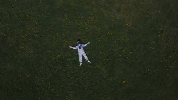 Astronauta acostado en la hierba mirando al cielo — Vídeos de Stock