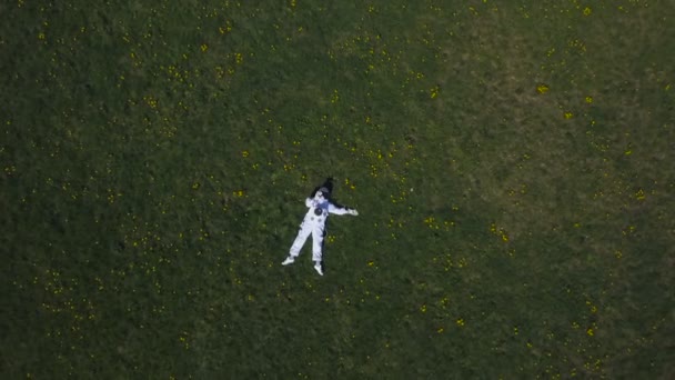 Космонавт лежит на траве, глядя в небо — стоковое видео