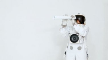 Bir teleskop uzaktan bakarak komik bir astronot portresi. Beyaz bir arka plan üzerinde.