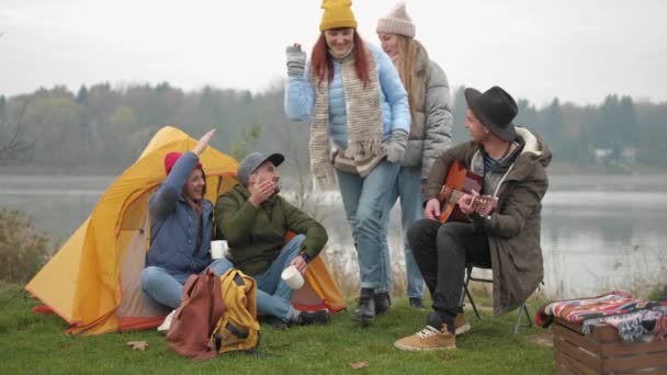 冒険、旅行、観光、人々 のコンセプト - キャンプでたき火の周りに座ってマシュマロと笑顔の友達のグループ — ストック動画