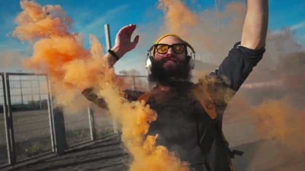 Porträt eines Hipsters mit gelber Brille. Straßentanz mit orangefarbenem Rauch. Zeitlupe — Stockvideo