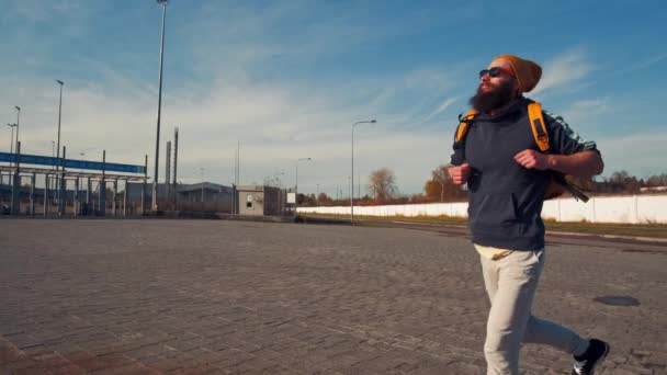 Νεαρός όμορφος βάναυσος γενειοφόρος άντρας τρέχει με σακίδιο, φθινοπωρινή μέρα, αστείο στυλ — Αρχείο Βίντεο