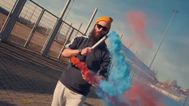 Portret van een hipster in een gele bril die op straat danst met oranje rook. Langzame beweging — Stockvideo