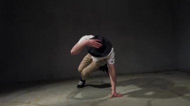 Genç adam break dans, sokak dansı konsepti. Dansçı zıplar, hareket eder, hareket eder ve duygular. Stüdyoda erkek dansçı, gri arka plan.
