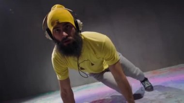 Dans eden genç mutlu sokak dansçısı çeşitli serbest stil hareketleri yapıyor, kulaklıkla müzik dinliyor, yakın plan sarı elbiseler giyiyor.