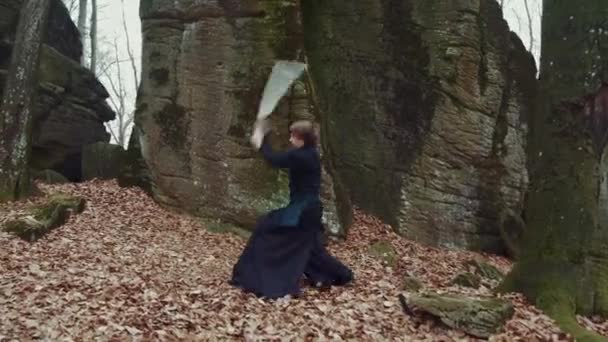 Man in traditional Japanese clothes, with a sword, a katana, trains martial arts in the forest background — 비디오