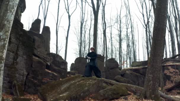 Uomo uniforme tradizionale tiene una katana in un 4k Sfocato sfondo verde foresta . — Video Stock