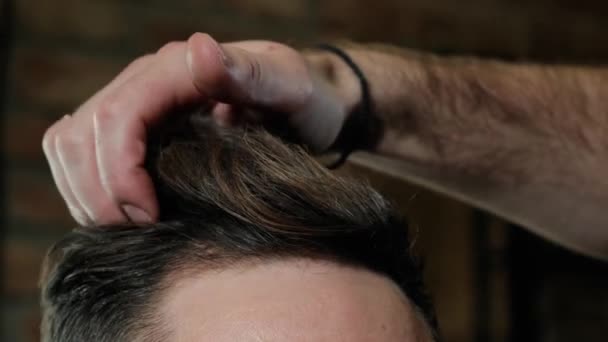 Male in hairdressing saloon, close shot. Stylist styling mens hair. Dark background — 비디오