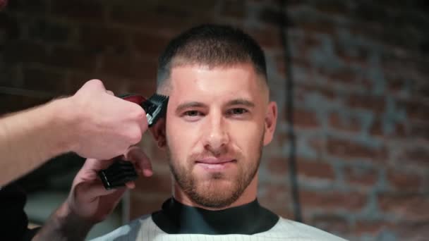 Vista de cerca en los hombres peinado en una peluquería con trimmer profesional. Corte de pelo para hombre en peluquería con cortador eléctrico. Aseo el cabello. Movimiento lento . — Vídeo de stock