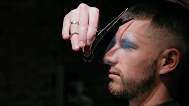 Mans hair cutting by barbers scissors and comb with barbershop logo behind in slow motion. Mans hands making male haircut in salon — Stock Video