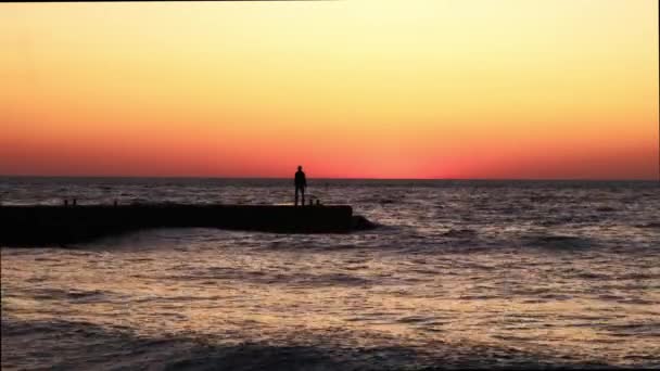 Een eenzame man bij zonsopkomst. Een man op het strand ontmoet de dageraad. zeegolf — Stockvideo