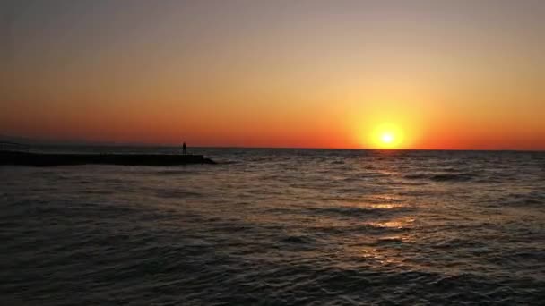 Um homem solitário ao nascer do sol. Um homem na praia conhece o amanhecer. onda do mar — Vídeo de Stock