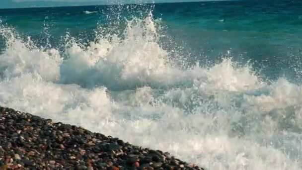 Die Wellen brechen an einem steinigen Strand, blaues Wasser — Stockvideo