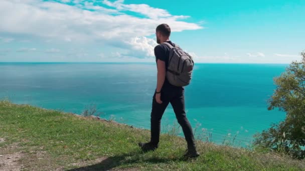 Macera, seyahat, turizm, yürüyüş ve insanlar konsepti - yaz aylarında deniz veya okyanusa bakan sırt çantalı bir adam — Stok video