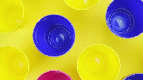 Von oben Farbe Kunststoffglas auf gelbem Hintergrund — Stockvideo