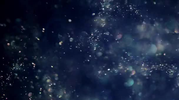 Blå glitter bakgrund skjuten i slow motion. Undervattenspartiklar som flyger och lyser i rampljuset, skjutna med skärpedjup. Space damm vacker bokeh abstrakt bakgrund — Stockvideo