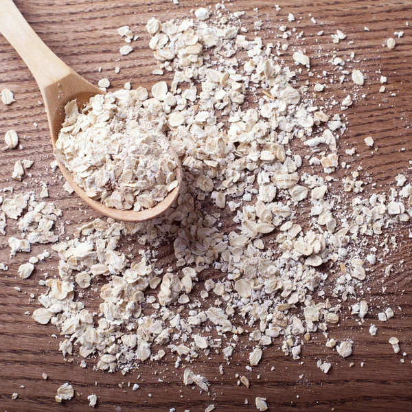 Copos de avena en cuchara de madera y sobre fondo de madera . —  Fotos de Stock