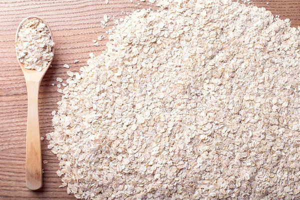 Organik yulaf ezmesi, yulaf gevreği ahşap arka plan, sağlıklı beslenme ve beslenme için kavram tahta kaşıkla yığını