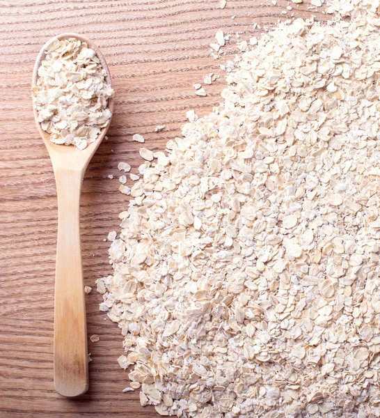 Organik yulaf ezmesi, yulaf gevreği ahşap arka plan üzerinde tahta kaşıkla yığını