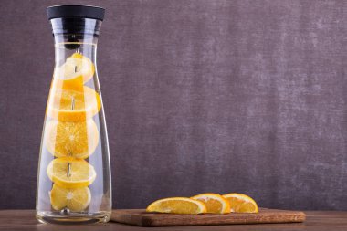 Portakal suyuyla yenileniyor. Orange içinde su dilimler. Bir cam kavanoza iç. Ahşap zemin üzerine ev yapımı limonata. 