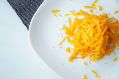 Beyaz tabakta rendelenmiş sarı peynir.